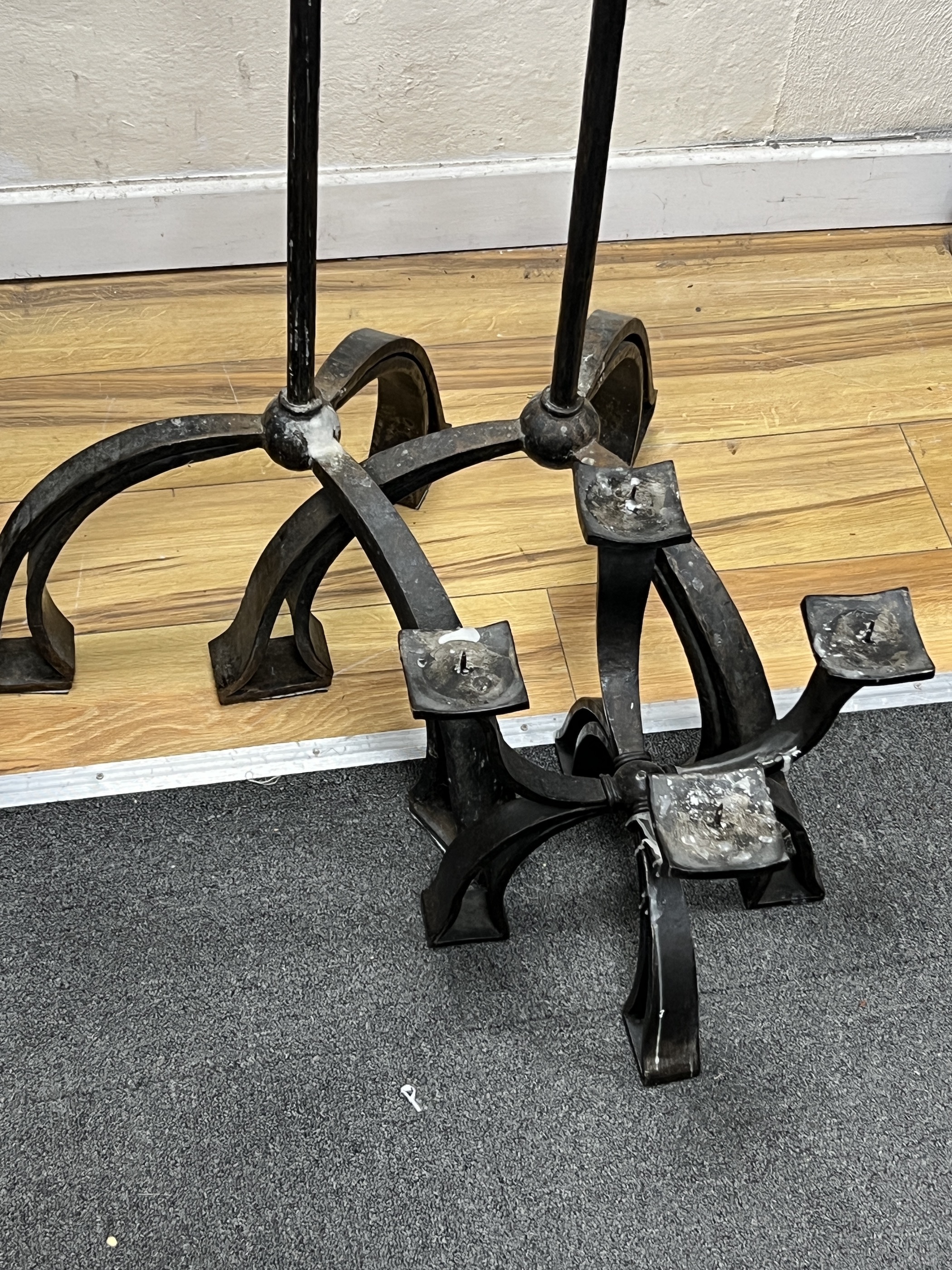 A pair of wrought iron three branch tripod pricket candlestands, height 146cm together with a matching four branch pricket candle holder